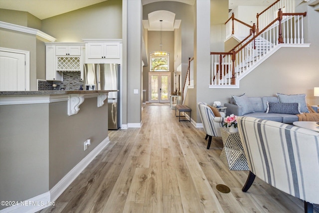 interior space featuring an inviting chandelier, light hardwood / wood-style floors, and high vaulted ceiling