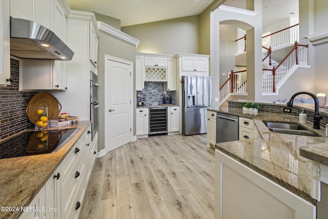 kitchen featuring dark stone counters, stainless steel appliances, sink, white cabinets, and wine cooler