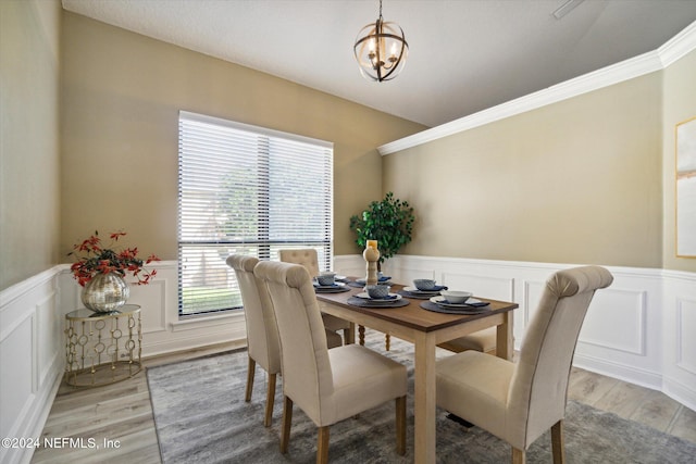 dining room with an inviting chandelier, ornamental molding, and light hardwood / wood-style flooring