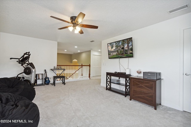 living area featuring a textured ceiling, light colored carpet, and ceiling fan