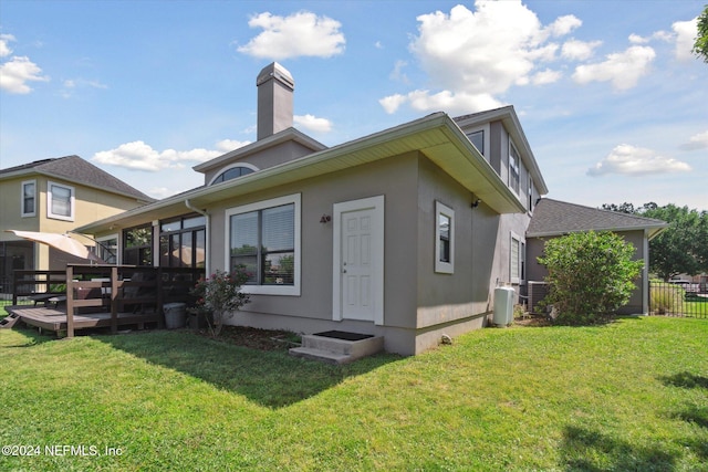 rear view of house featuring a sunroom, a yard, and a wooden deck