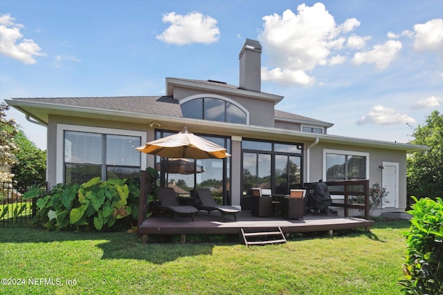 back of property featuring a lawn, a wooden deck, and a sunroom