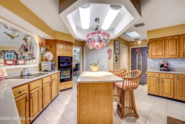 kitchen with black appliances, tasteful backsplash, light tile patterned floors, a skylight, and a center island