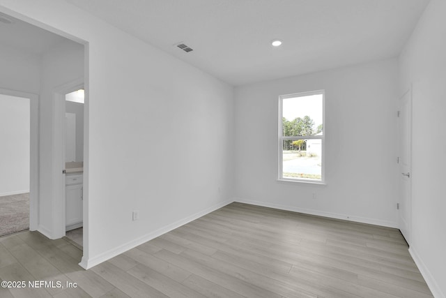 unfurnished room featuring light wood finished floors, recessed lighting, visible vents, and baseboards