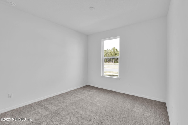 unfurnished room featuring carpet floors and baseboards