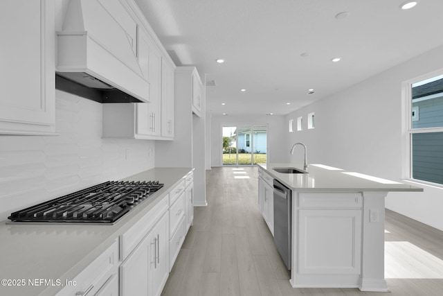 kitchen with custom exhaust hood, white cabinetry, a sink, gas cooktop, and dishwasher