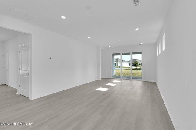 spare room featuring light wood finished floors, baseboards, visible vents, and recessed lighting