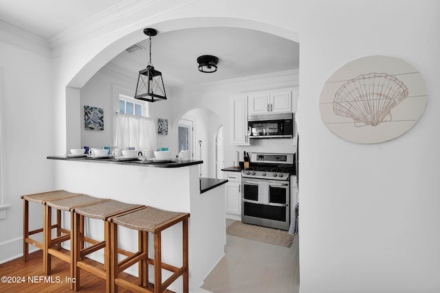 kitchen with white cabinets, crown molding, kitchen peninsula, and appliances with stainless steel finishes