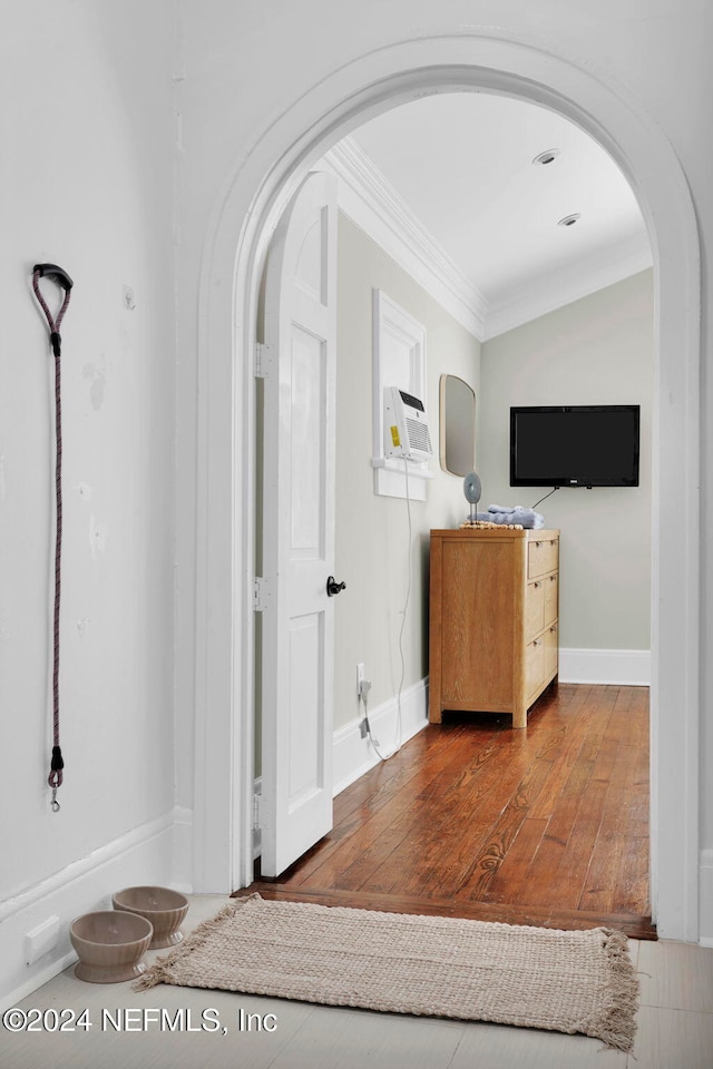 corridor with lofted ceiling, hardwood / wood-style flooring, and ornamental molding