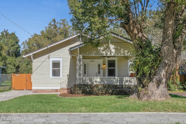 view of front of property featuring ceiling fan, a porch, and a front lawn