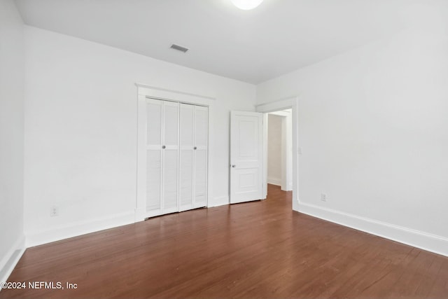 unfurnished bedroom featuring a closet and dark hardwood / wood-style flooring