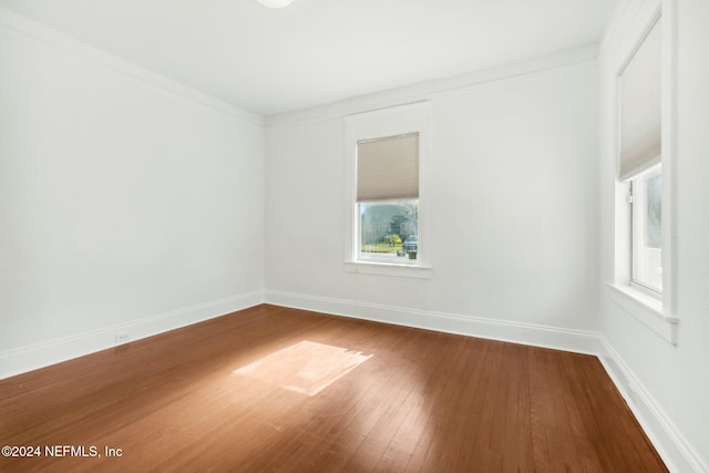 empty room with hardwood / wood-style floors and crown molding