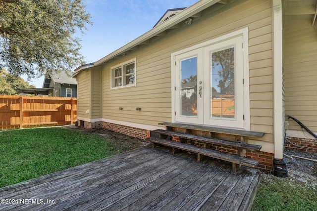 back of house featuring a lawn, a wooden deck, and french doors