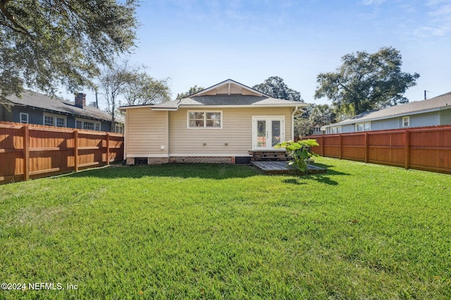 back of property with a lawn and french doors