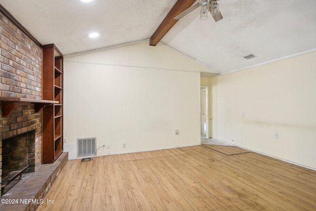 unfurnished living room featuring light hardwood / wood-style floors, a textured ceiling, ceiling fan, a fireplace, and lofted ceiling with beams