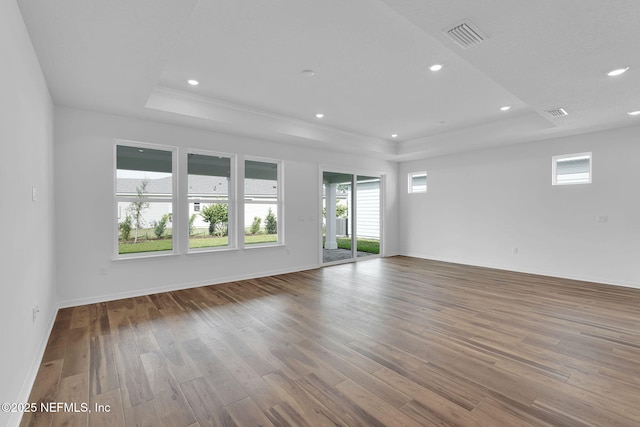 unfurnished room featuring visible vents, a tray ceiling, wood finished floors, and recessed lighting