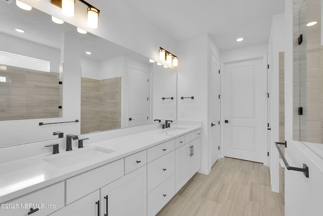 full bathroom with double vanity, recessed lighting, a sink, and tiled shower