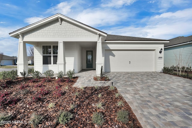 view of front of home with a garage, roof with shingles, decorative driveway, and covered porch