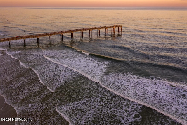 view of dock with a water view and a beach view