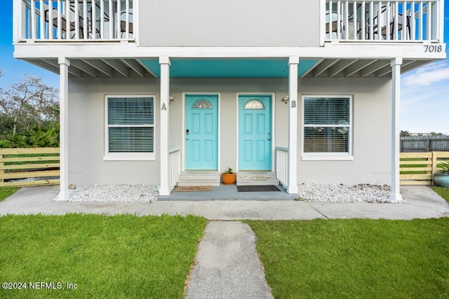 property entrance with a balcony and a lawn