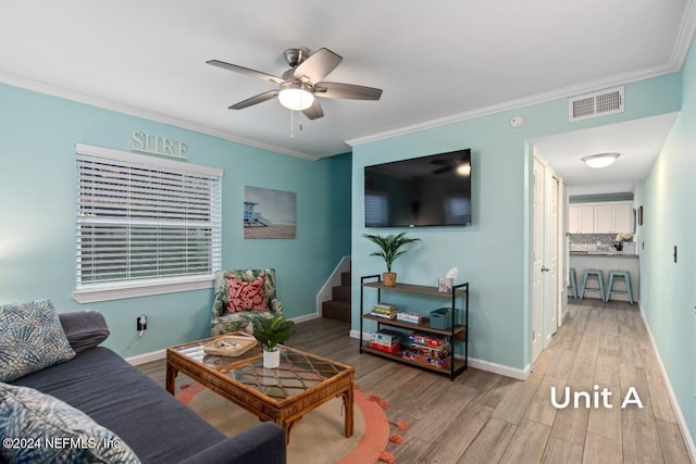 living room with ornamental molding, ceiling fan, and light wood-type flooring