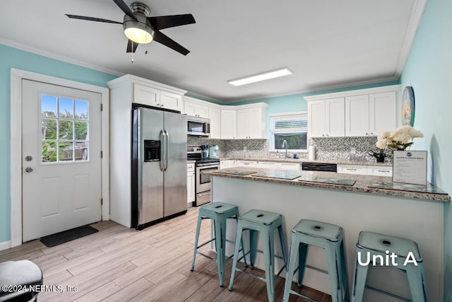 kitchen with stone counters, appliances with stainless steel finishes, ornamental molding, light hardwood / wood-style floors, and white cabinets