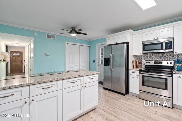 kitchen with tasteful backsplash, crown molding, light wood-type flooring, appliances with stainless steel finishes, and white cabinets