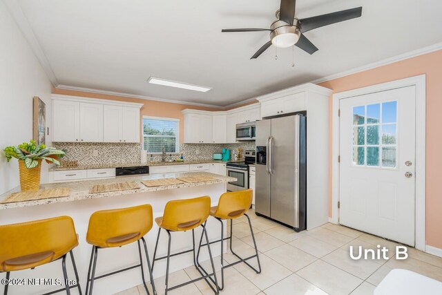 kitchen featuring a kitchen breakfast bar, white cabinetry, appliances with stainless steel finishes, and crown molding