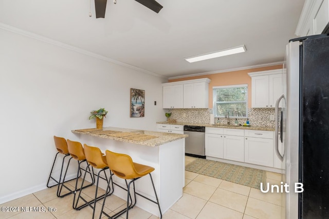 kitchen featuring stainless steel appliances, white cabinetry, a kitchen bar, and decorative backsplash