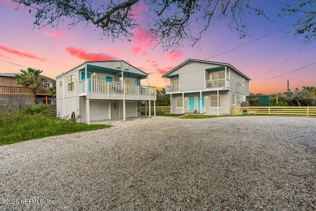 back house at dusk with a balcony and a garage