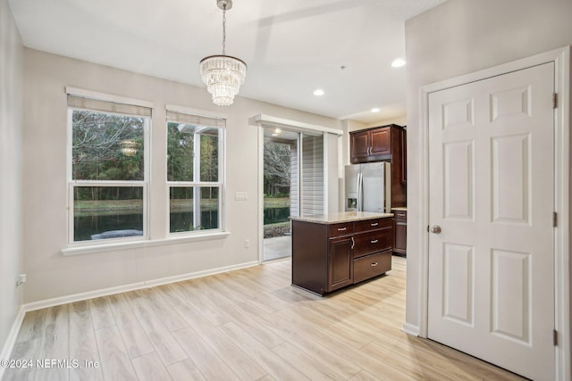 kitchen featuring dark brown cabinetry, stainless steel fridge with ice dispenser, a chandelier, pendant lighting, and a kitchen island