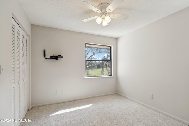 unfurnished bedroom featuring a closet, carpet, a textured ceiling, and ceiling fan