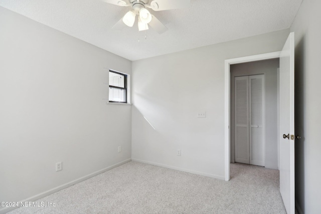 empty room featuring ceiling fan, light colored carpet, and a textured ceiling