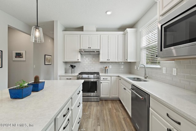 kitchen with white cabinetry, appliances with stainless steel finishes, decorative backsplash, sink, and light hardwood / wood-style flooring