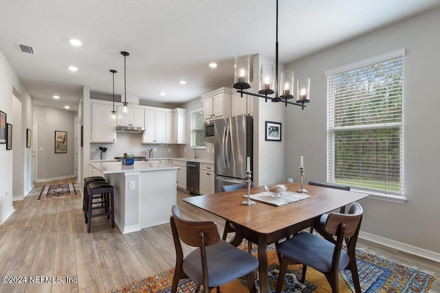 dining area featuring a chandelier, light hardwood / wood-style flooring, a healthy amount of sunlight, and sink