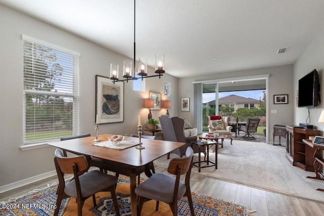 dining area featuring plenty of natural light, a notable chandelier, and light hardwood / wood-style flooring