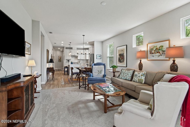 living room featuring plenty of natural light, a chandelier, and light hardwood / wood-style flooring