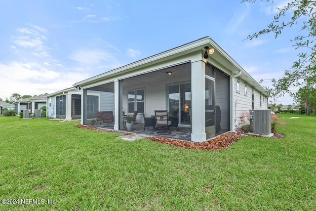 rear view of property featuring a patio, central AC, a lawn, and a sunroom