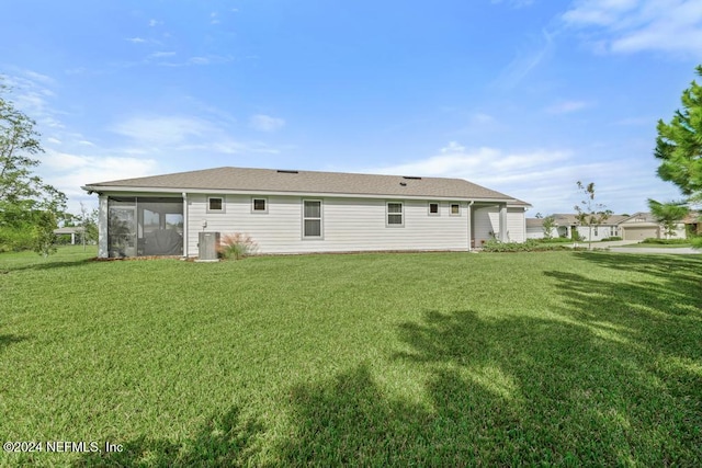 back of property with central AC unit, a sunroom, and a yard