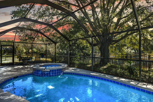 pool at dusk featuring an in ground hot tub and a lanai