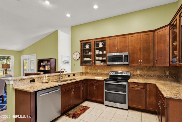 kitchen featuring appliances with stainless steel finishes, kitchen peninsula, sink, and light stone countertops