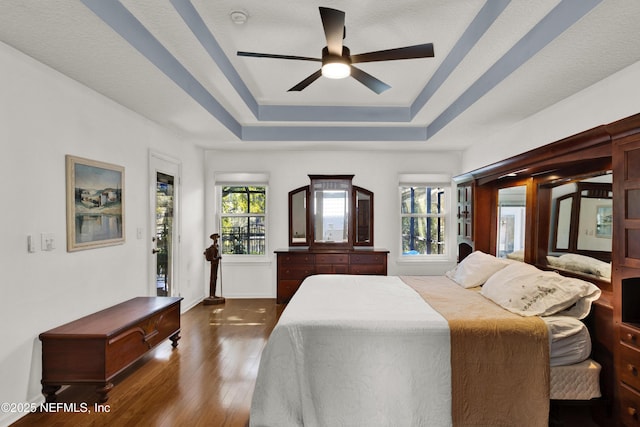 bedroom featuring ceiling fan, dark hardwood / wood-style floors, and a raised ceiling