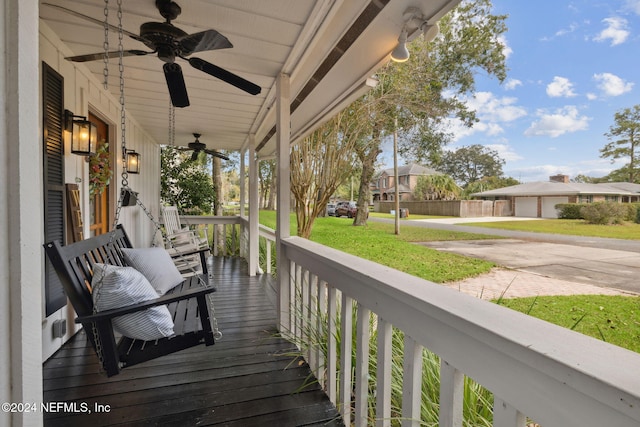 wooden deck featuring a lawn, ceiling fan, and a porch