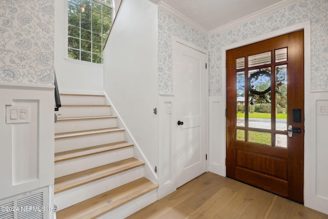 entrance foyer featuring plenty of natural light, light hardwood / wood-style floors, a textured ceiling, and ornamental molding