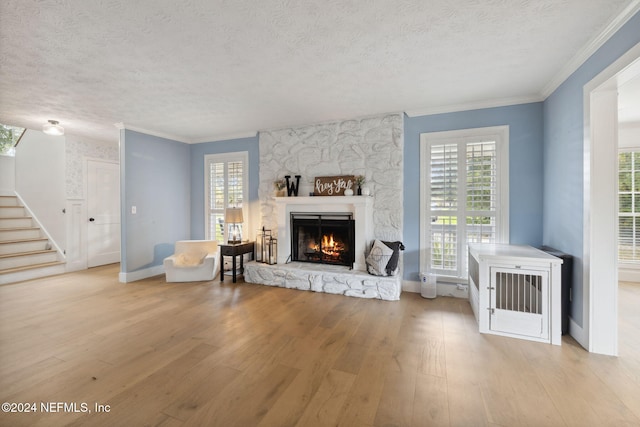 living room with a textured ceiling, light hardwood / wood-style floors, ornamental molding, and a fireplace