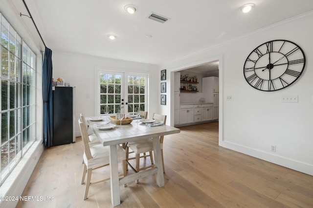 dining space with a wealth of natural light, french doors, light hardwood / wood-style floors, and ornamental molding