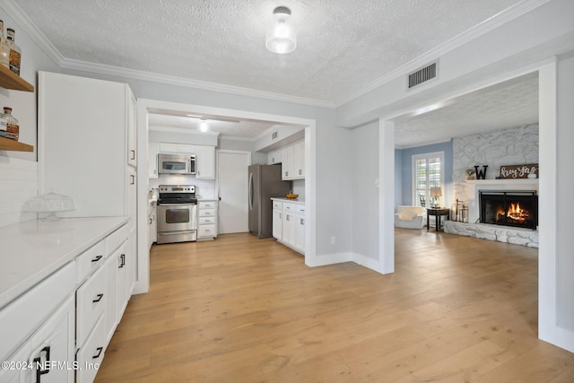 kitchen with white cabinetry, light hardwood / wood-style flooring, stainless steel appliances, and a textured ceiling