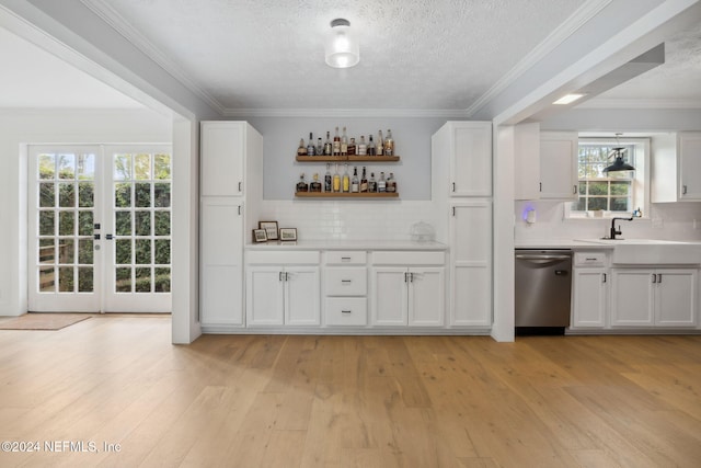 bar featuring decorative backsplash, stainless steel dishwasher, sink, white cabinets, and light hardwood / wood-style floors