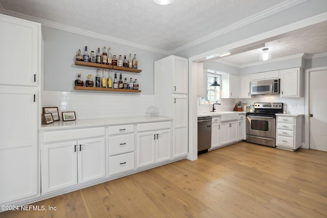 kitchen with white cabinetry, stainless steel appliances, tasteful backsplash, crown molding, and light hardwood / wood-style floors