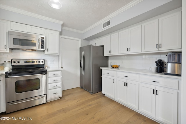 kitchen with white cabinetry, crown molding, a textured ceiling, appliances with stainless steel finishes, and light wood-type flooring